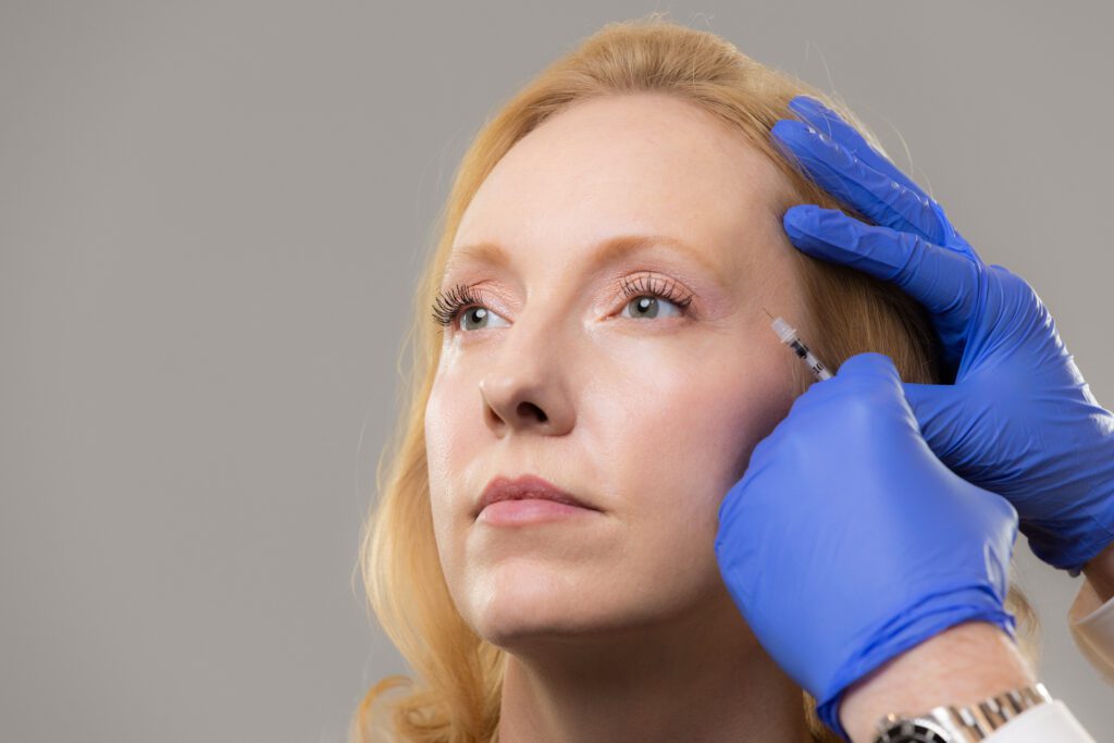 Lady receiving therapeutic injectable on temple to relieve headache